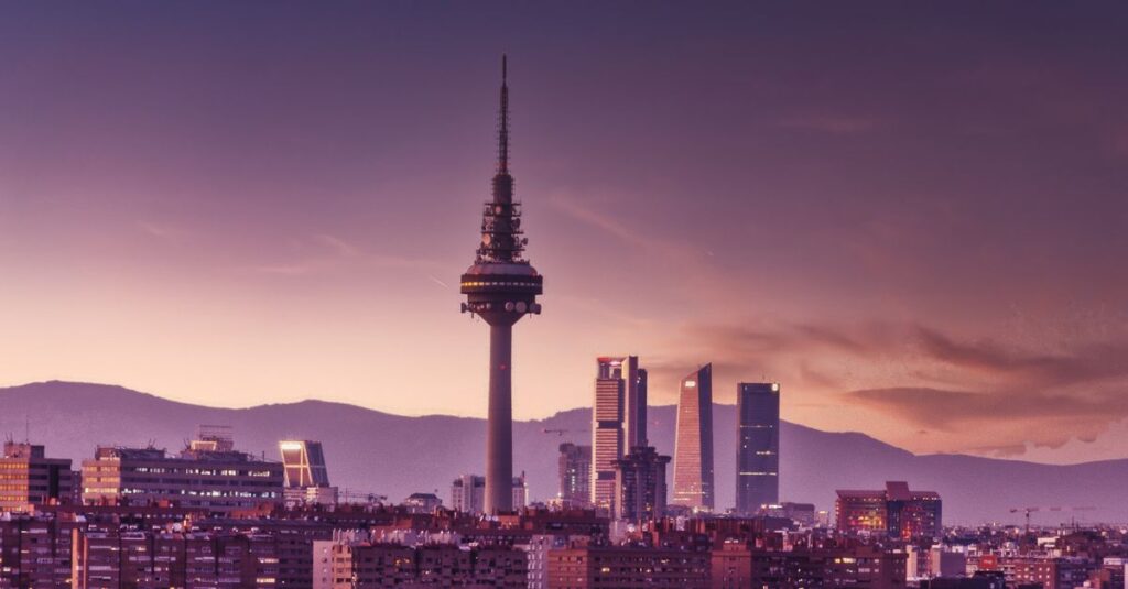 Stunning view of Madrid's skyline at twilight featuring the iconic Torrespaña Tower and mountains in the background.