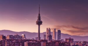 Stunning view of Madrid's skyline at twilight featuring the iconic Torrespaña Tower and mountains in the background.