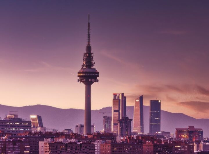 Stunning view of Madrid's skyline at twilight featuring the iconic Torrespaña Tower and mountains in the background.