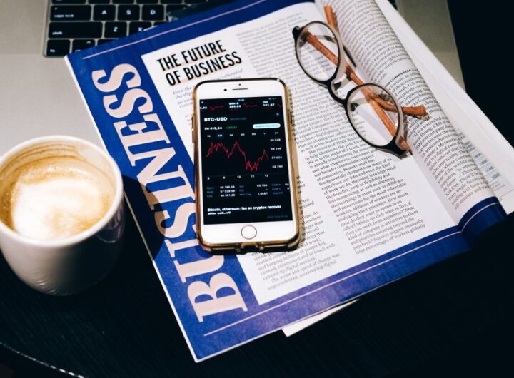 A business setup with a laptop, coffee, phone, and newspaper. Perfect for finance themes.